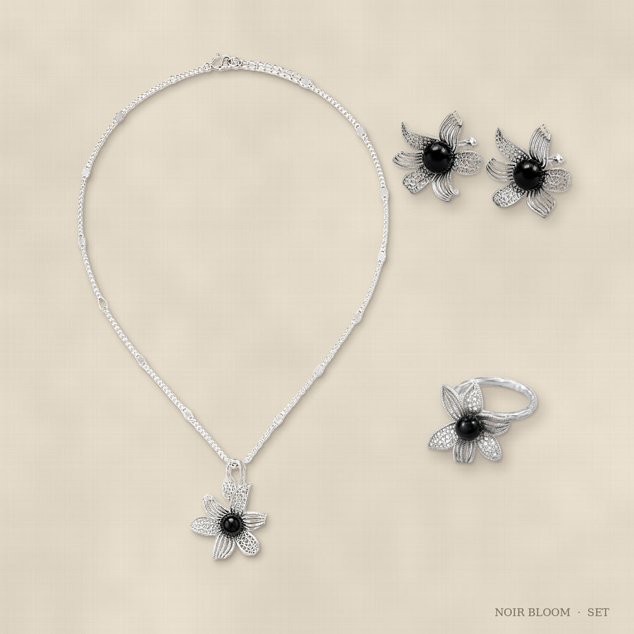 Noir Bloom jewelry set flat lay – ring, earrings and necklace arranged together