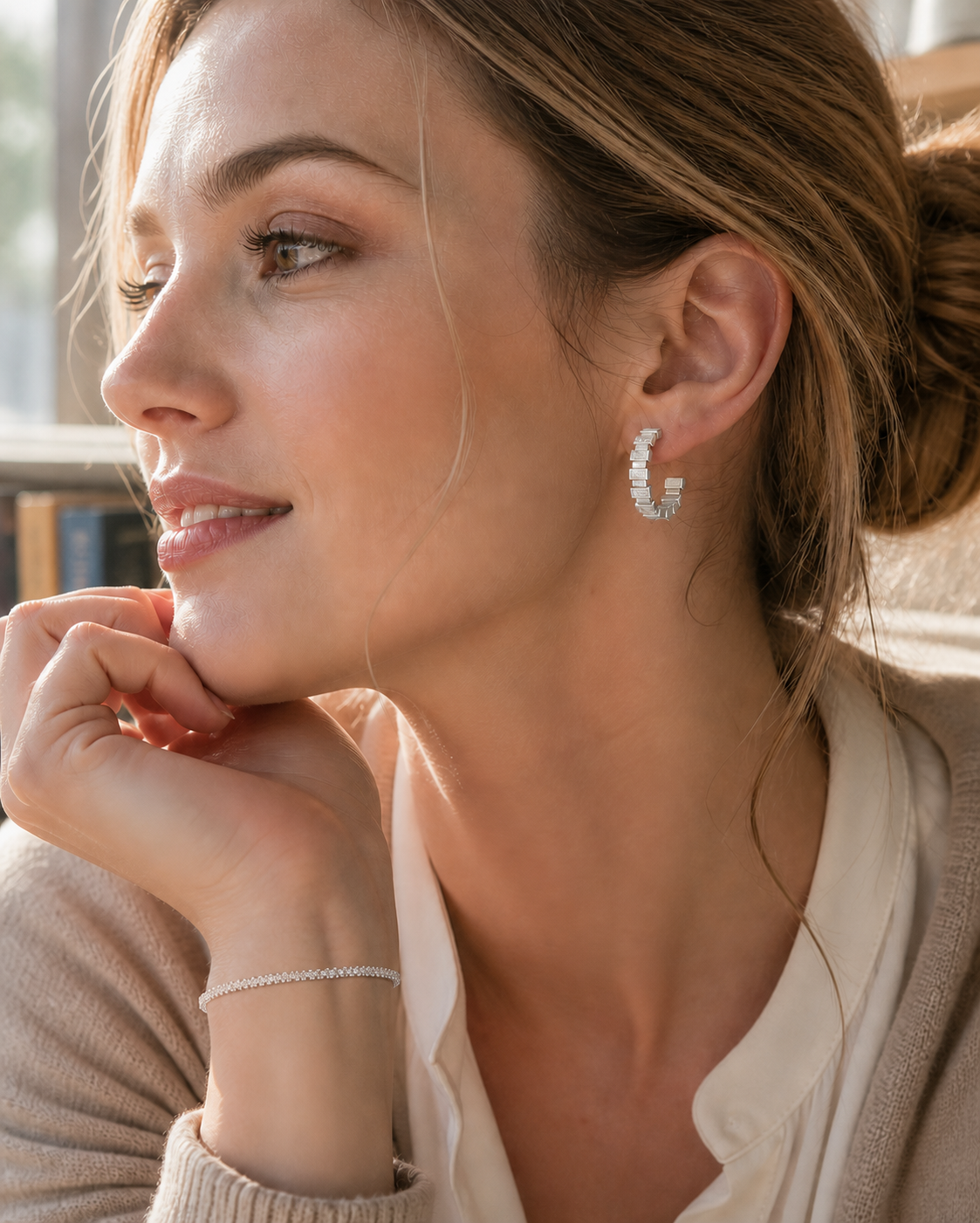 European woman wearing silver geometric hoop earrings with a slim silver bracelet in an everyday setting